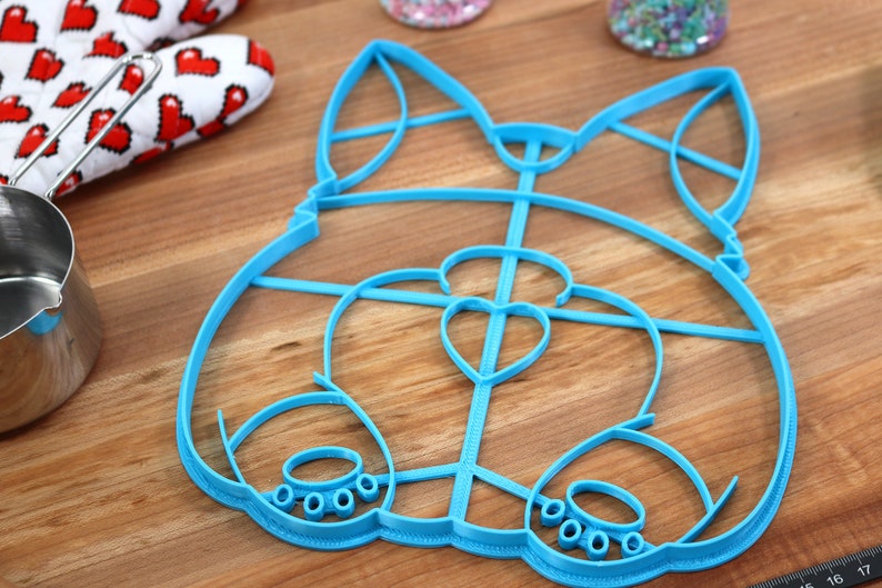 May include: A blue plastic cookie cutter shaped like a cartoon dog. The cutter has a heart-shaped nose and paw prints on the bottom.