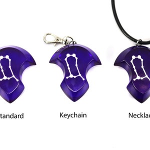 May include: Three versions of a purple pendant featuring the Gemini constellation in white. The pendant is available as a standard piece, a keychain, and a necklace.