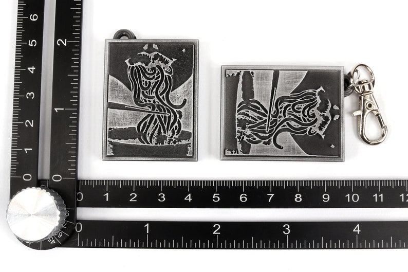 May include: Two silver metal keychains with a design of noodles and chopsticks. The keychains are attached to a silver metal ring.