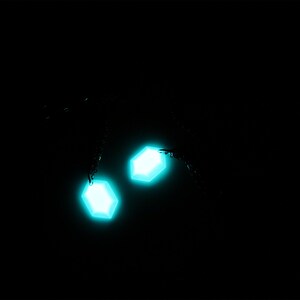 May include: Two glowing turquoise hexagonal shapes against a black background.