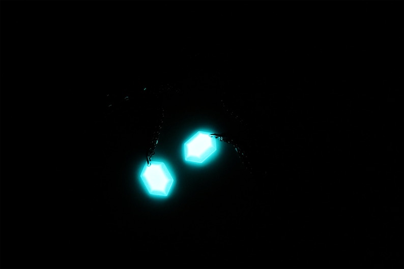 May include: Two glowing turquoise hexagonal shapes against a black background.