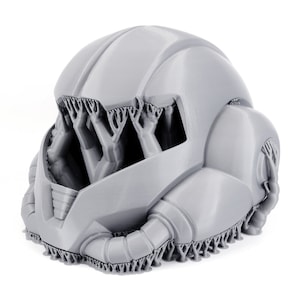 May include: A 3D printed gray helmet with a detailed design. The helmet has a textured surface and intricate details.