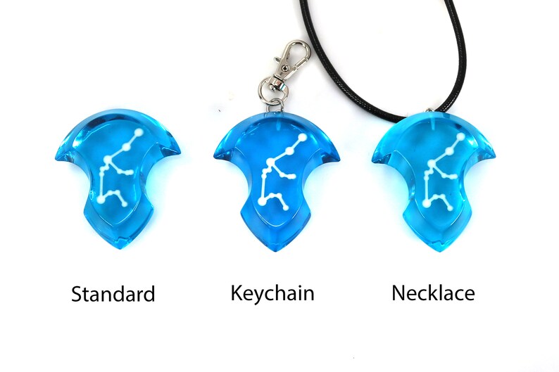 May include: Three versions of a blue pendant with a white constellation design. The pendant is available as a standard piece, a keychain, and a necklace.