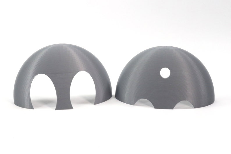 May include: Two gray 3D printed plastic hemispheres with cutouts. One hemisphere has two large cutouts and the other has three smaller cutouts and a single round hole.