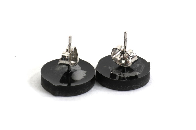 May include: A pair of black round stud earrings with silver posts and backs.