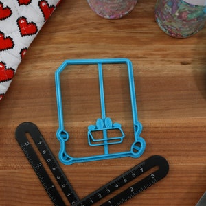 May include: A blue plastic cookie cutter shaped like a vintage car. The cutter has a detailed design with a window and wheels.