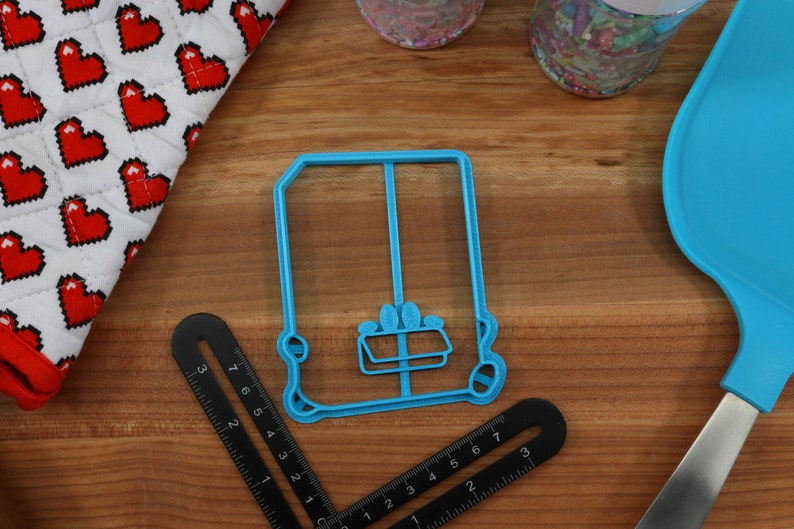 May include: A blue plastic cookie cutter shaped like a vintage car. The cutter has a detailed design with a window and wheels.
