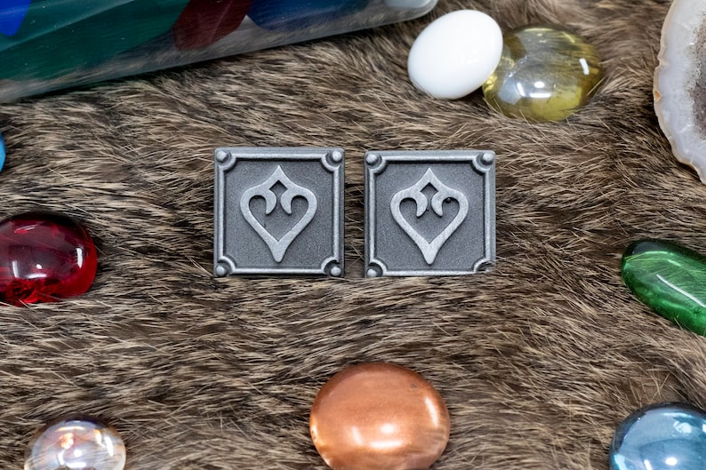Peut inclure: Deux &eacute;pingles en m&eacute;tal argent&eacute; avec un motif d&eacute;coratif en forme de c&oelig;ur. Les &eacute;pingles sont de forme carr&eacute;e et ont une bordure sur&eacute;lev&eacute;e.