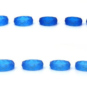 May include: Eight blue silicone rings with a geometric design and a white graphic of a stylized eye. The rings are arranged in two rows of four.