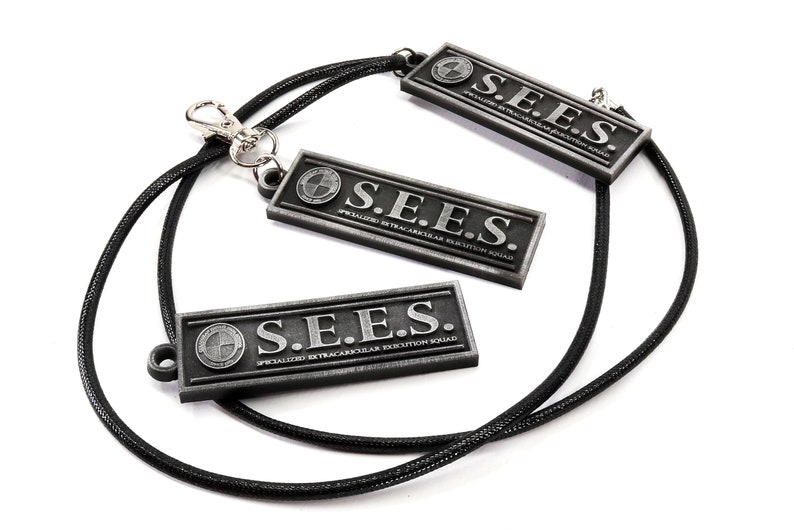 May include: A black lanyard with three silver metal tags that read "S.E.E.S. SPECIALIZED EXTRACURRICULAR EXECUTION SQUAD".