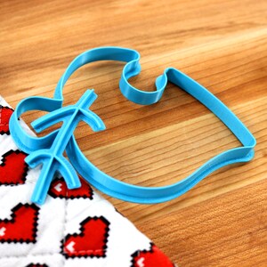 May include: A blue plastic cookie cutter shaped like a fish with a decorative design on the tail.