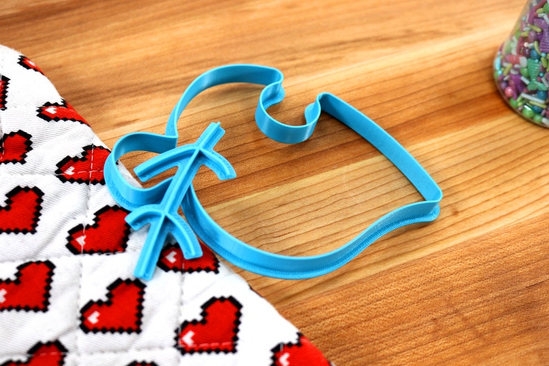 May include: A blue plastic cookie cutter shaped like a fish with a decorative design on the tail.