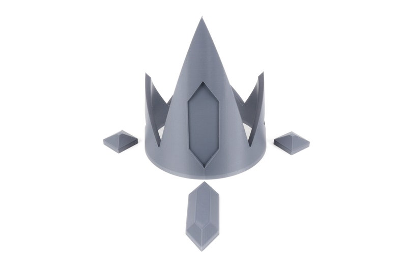 May include: A gray 3D printed crown with a pointed top and four smaller gray 3D printed pieces attached to the base.