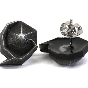 May include: A pair of silver geometric stud earrings. The earrings are made of a textured metal and have a unique, modern design.