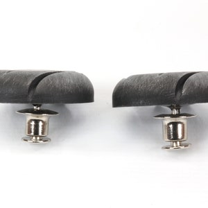 Peut inclure: Deux boutons-pression en plastique noir avec une base en m&eacute;tal argent&eacute;. Les boutons-pression ont une surface textur&eacute;e et une forme circulaire.