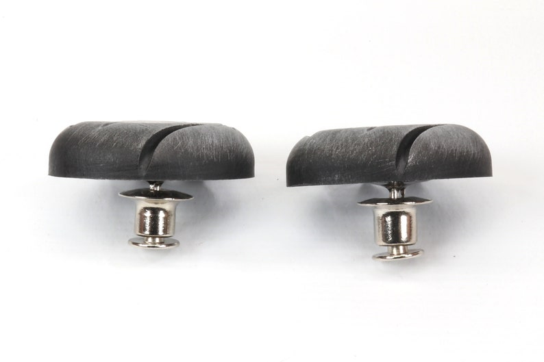 Peut inclure: Deux boutons-pression en plastique noir avec une base en m&eacute;tal argent&eacute;. Les boutons-pression ont une surface textur&eacute;e et une forme circulaire.