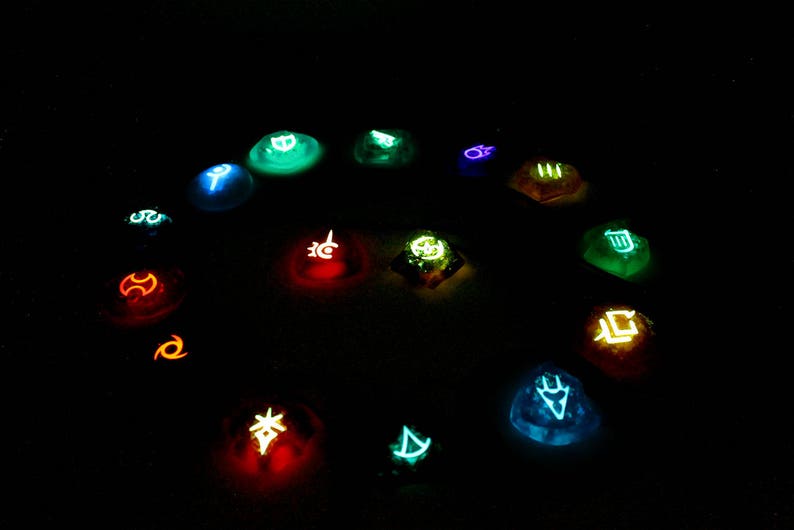 May include: A collection of 14 glowing, colorful, round, resin dice with various symbols on each face. The dice are arranged in a circle on a dark background.