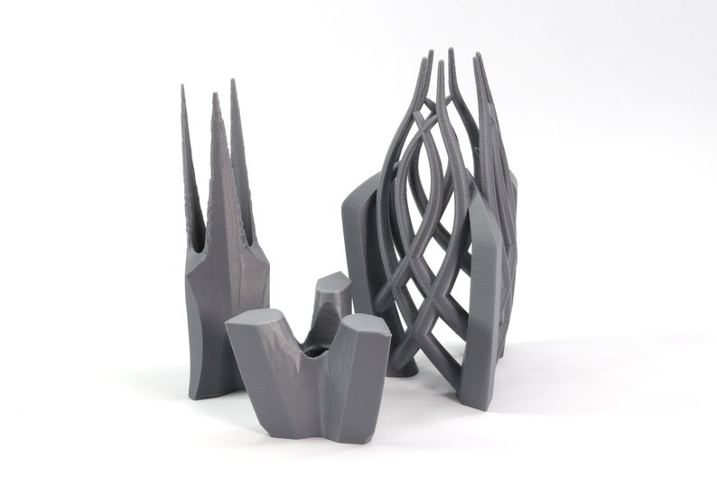 May include: Three gray 3D printed sculptures. The sculptures are abstract and have a geometric design. The sculptures are made of a smooth, matte material.