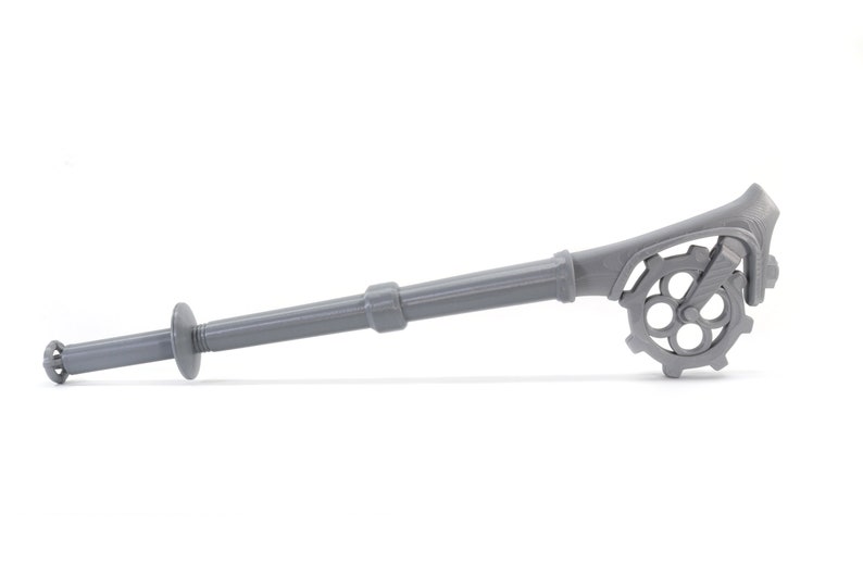 May include: A gray plastic tool with a long handle and a gear-like mechanism at the end. The tool is designed for attaching drywall.