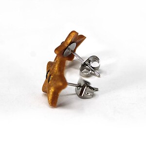 May include: A pair of gold star-shaped earrings with silver posts and backs.