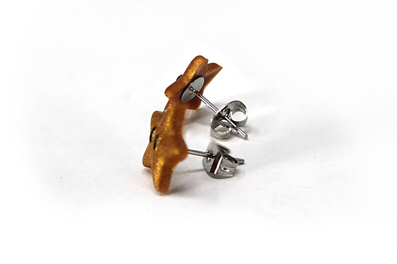 May include: A pair of gold star-shaped earrings with silver posts and backs.