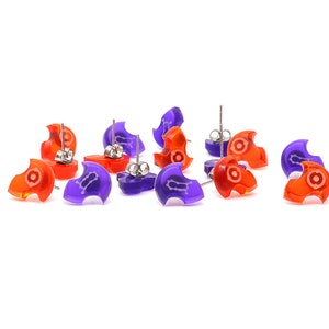 May include: A set of 10 earrings, 5 are orange and 5 are purple. Each earring is shaped like a crescent moon with a small white design in the center. The earrings have silver posts.