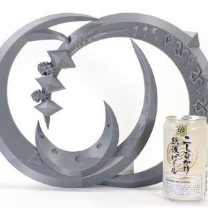 May include: A gray 3D printed sculpture of two interlocking crescent moons with intricate designs. The sculpture is about the size of a standard can of beer.