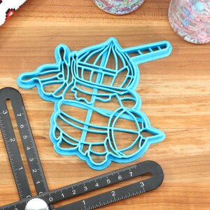 May include: Blue plastic cookie cutter shaped like a unicorn with a horn, a crown, and a tail.