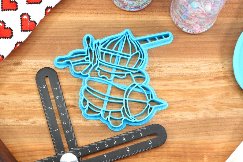 May include: Blue plastic cookie cutter shaped like a unicorn with a horn, a crown, and a tail.