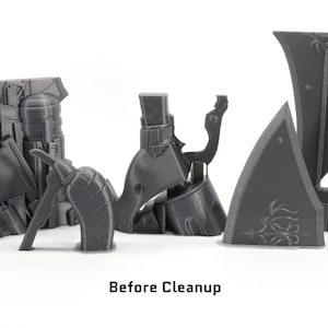 May include: A set of gray 3D printed plastic pieces, likely for a model or toy. The pieces are arranged on a white surface, with the text "Before Cleanup" below them.