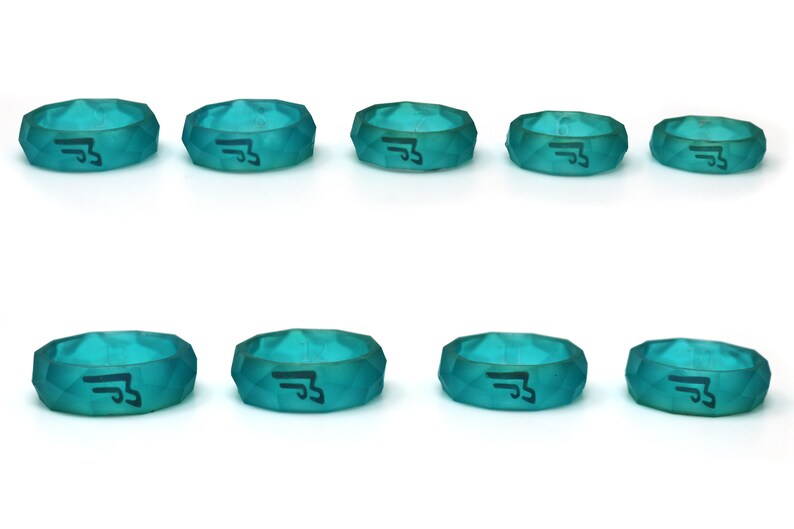 May include: Eight teal blue silicone rings with a black symbol on each. The rings are different sizes and have a faceted design.