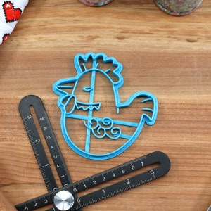 Puede incluir: Cortador de galletas de pl&aacute;stico azul con forma de pollo de dibujos animados sosteniendo un huevo. El cortador tiene un dise&ntilde;o detallado con cresta, papada y plumas.