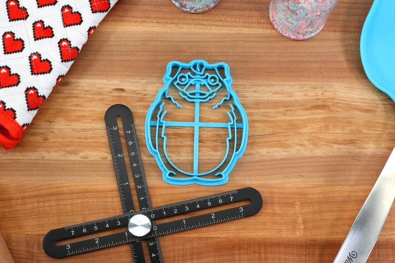 May include: Blue plastic cookie cutter shaped like a cartoon character with large eyes and a round body.