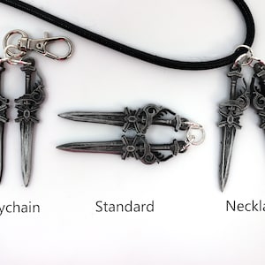 May include: A collection of silver-colored dagger pendants, including a keychain, a standard version, and a necklace. The daggers have ornate handles and are displayed on a white surface with the text "Keychain", "Standard", and "Necklace".