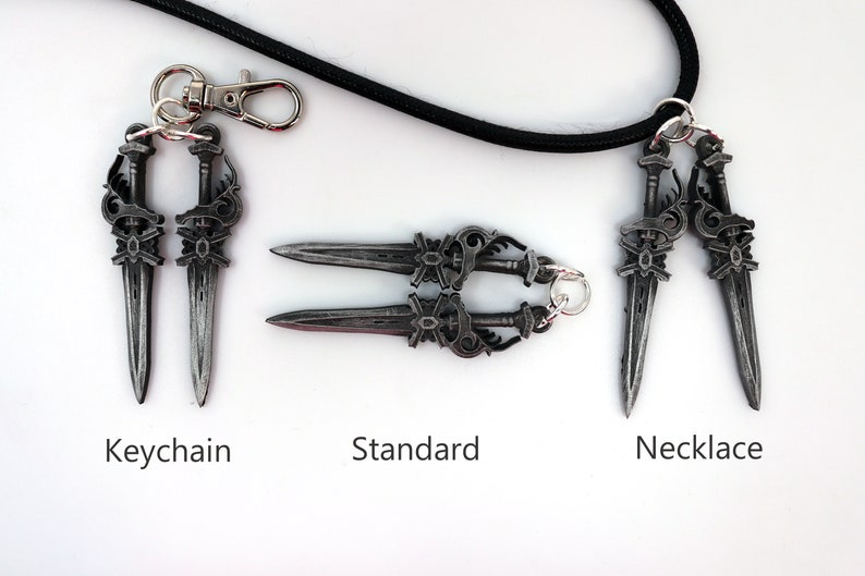 May include: A collection of silver-colored dagger pendants, including a keychain, a standard version, and a necklace. The daggers have ornate handles and are displayed on a white surface with the text "Keychain", "Standard", and "Necklace".