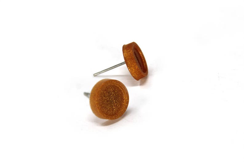 May include: A pair of gold-toned stud earrings with a textured finish.