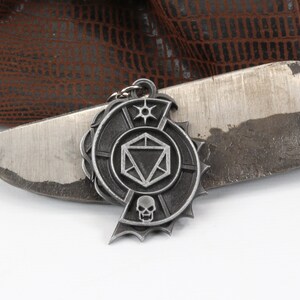 May include: A silver metal keychain with a skull, a 20-sided die, and a star design.