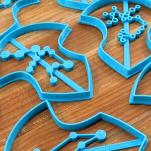 Puede incluir: Un conjunto de cortadores de galletas de pl&aacute;stico azul con forma de copo de nieve con un dise&ntilde;o geom&eacute;trico. Los cortadores est&aacute;n sobre una superficie de madera.