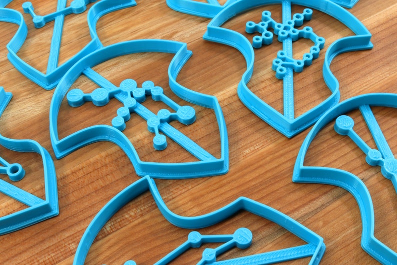 Puede incluir: Un conjunto de cortadores de galletas de pl&aacute;stico azul con forma de copo de nieve con un dise&ntilde;o geom&eacute;trico. Los cortadores est&aacute;n sobre una superficie de madera.