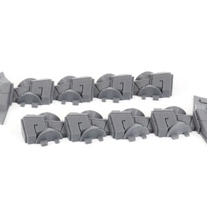 May include: A set of 12 gray plastic wall pieces with a geometric design. The pieces are designed to be used as a border or trim for a model or diorama.
