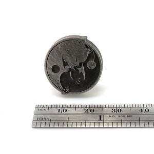 May include: A silver-toned metal pin with a yin yang design featuring two stylized animals. The pin is approximately 2 cm in diameter.