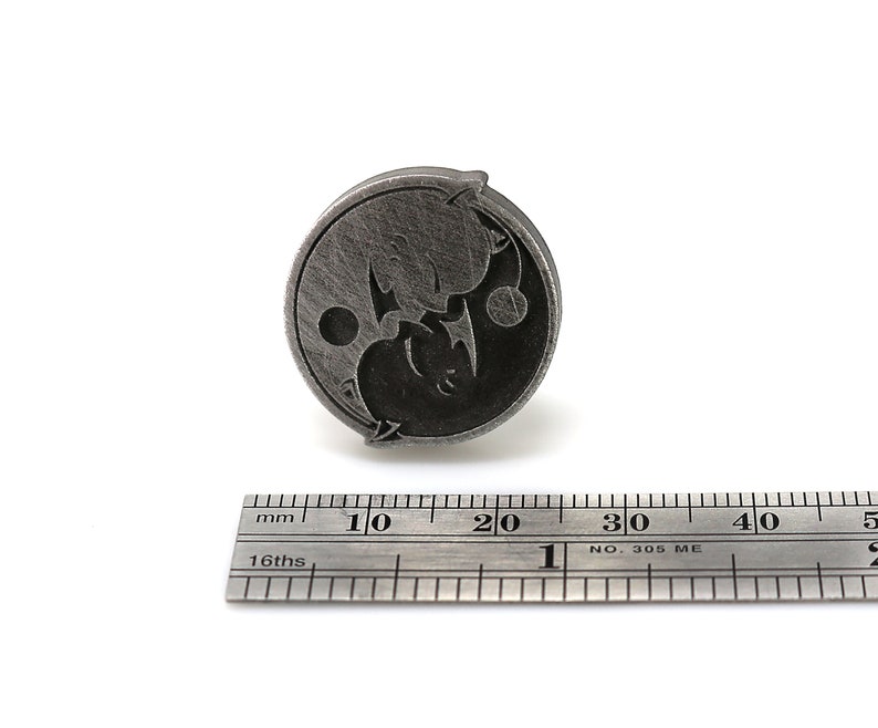May include: A silver-toned metal pin with a yin yang design featuring two stylized animals. The pin is approximately 2 cm in diameter.