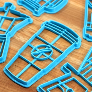 May include: A set of blue plastic cookie cutters shaped like a coffee pot, a coffee cup, a coffee bean, and a coffee shop sign.
