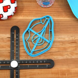 May include: A blue plastic cookie cutter shaped like a steak with a spiral design in the center.