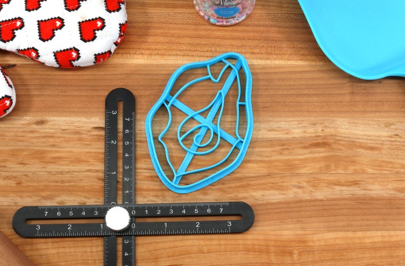 May include: A blue plastic cookie cutter shaped like a steak with a spiral design in the center.