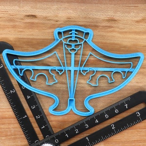 May include: A blue plastic cookie cutter shaped like a manta ray. The cutter is about 4 inches wide and 3 inches tall.