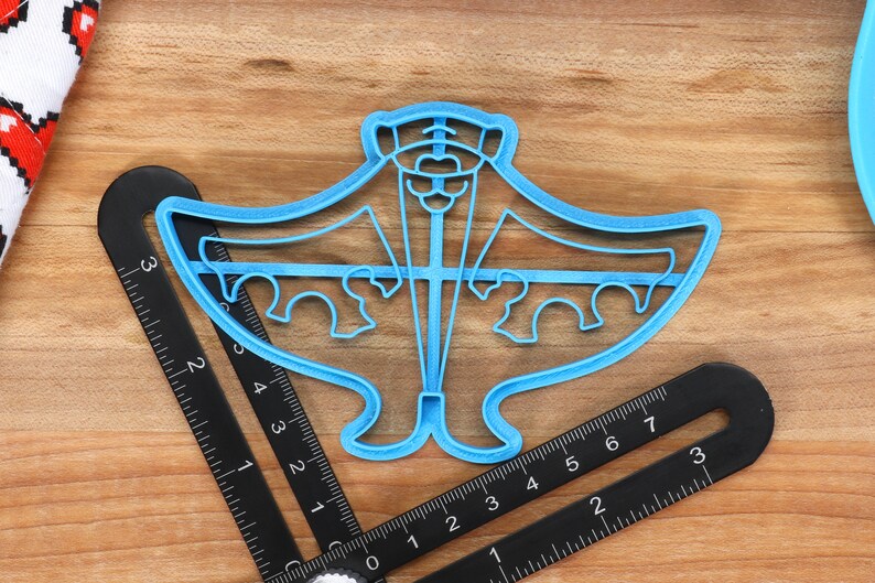 May include: A blue plastic cookie cutter shaped like a manta ray. The cutter is about 4 inches wide and 3 inches tall.