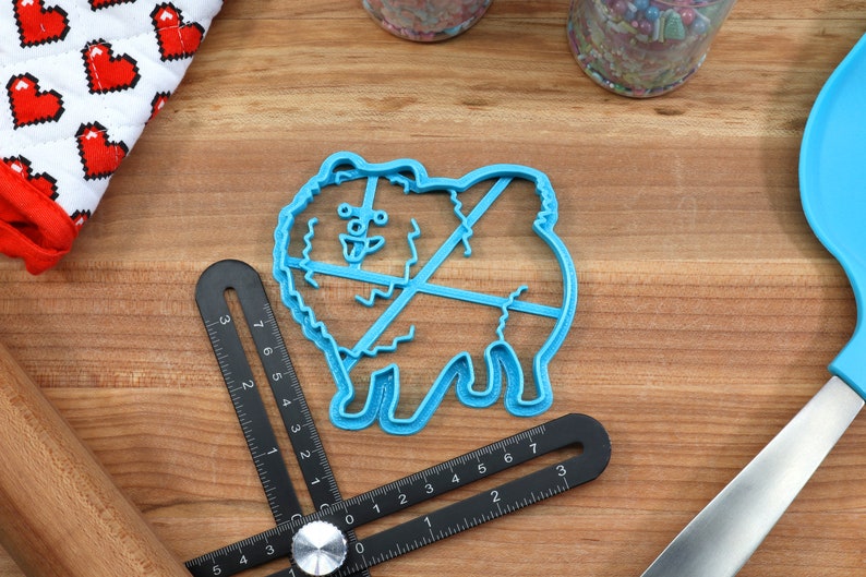 May include: Blue plastic cookie cutter shaped like a Pomeranian dog. The cutter has a detailed design with a fluffy tail and paws.