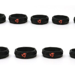 May include: Eight black silicone rings with a red and orange swirl design. The rings are all different sizes.