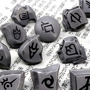 May include: A collection of 14 silver-colored metal tokens with various symbols and designs. The tokens are scattered on a white surface with Japanese text.